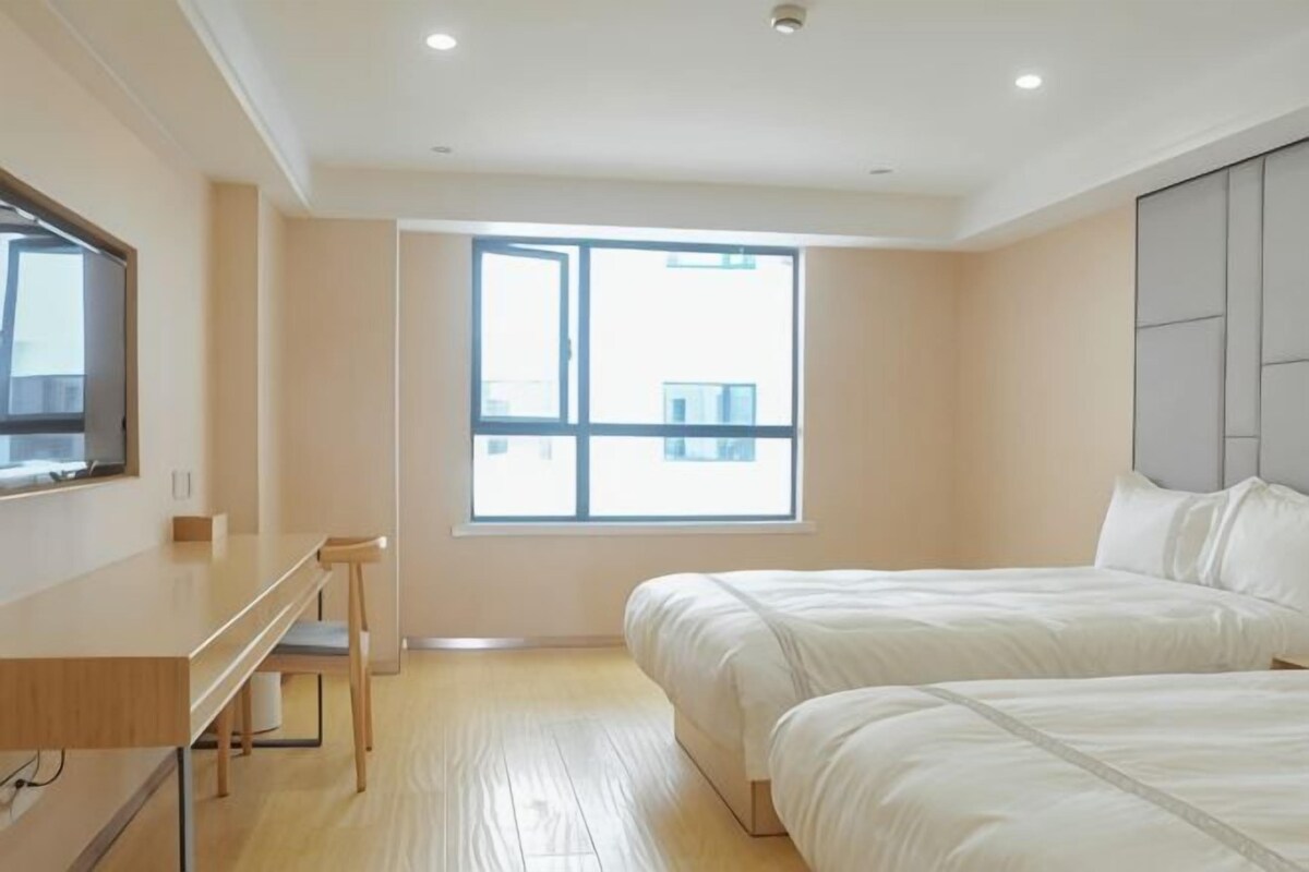 A bedroom with a bed, a desk, and a window.