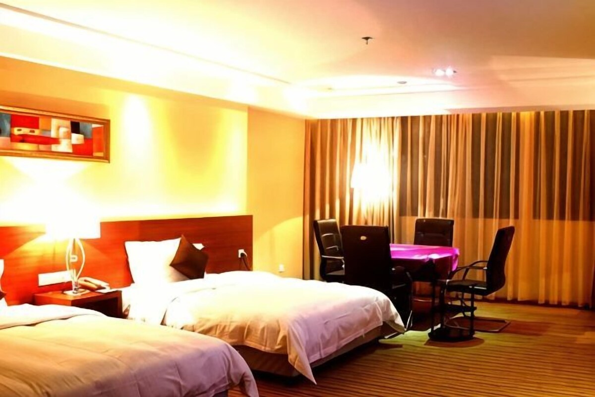 A hotel room with two beds, a desk, and a chair.