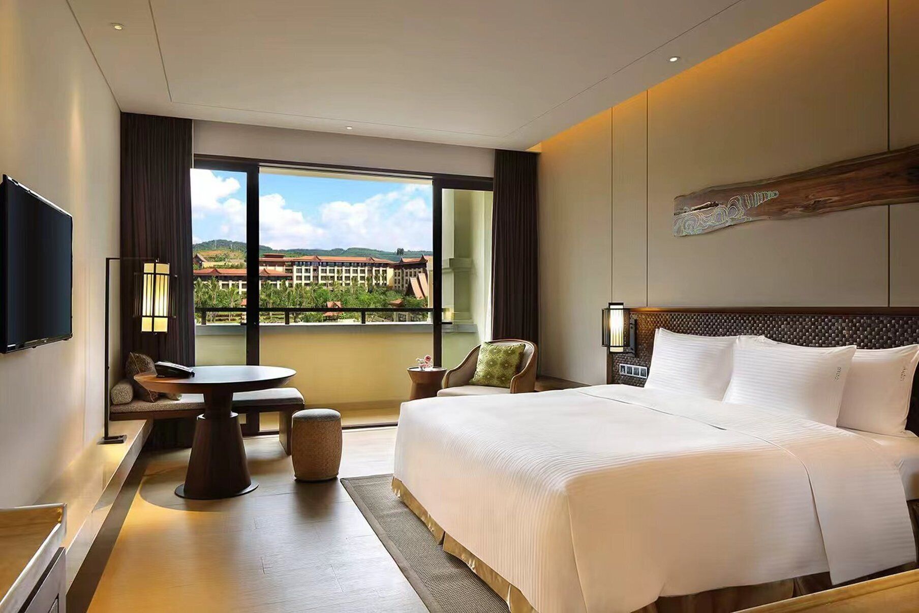 A hotel room with a large bed, a desk, a chair, and a TV.