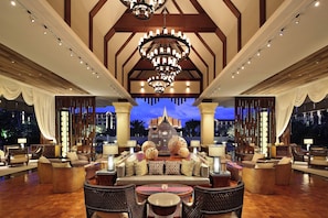 A spacious lobby with a central seating area, chandeliers, and a view of a building in the background. - Crowne Plaza Resort Xishuangbanna Parkview by IHG (Xishuangbanna Dai)