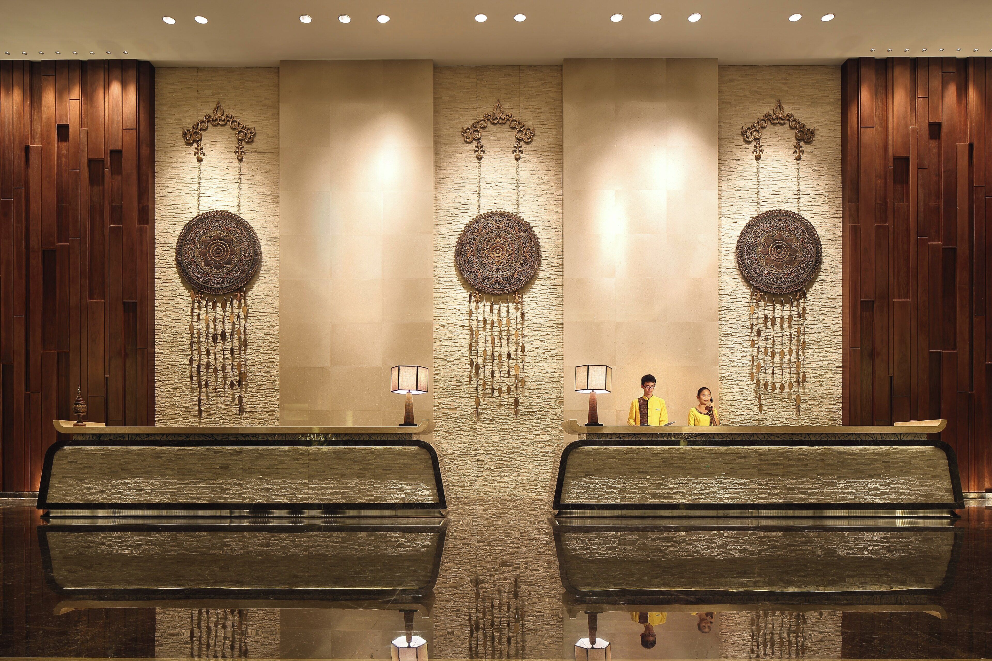 A reception area with a modern design, featuring a reception desk, two symmetrical wall decorations, and a textured wall.