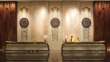 A reception area with a modern design, featuring a reception desk, two symmetrical wall decorations, and a textured wall.