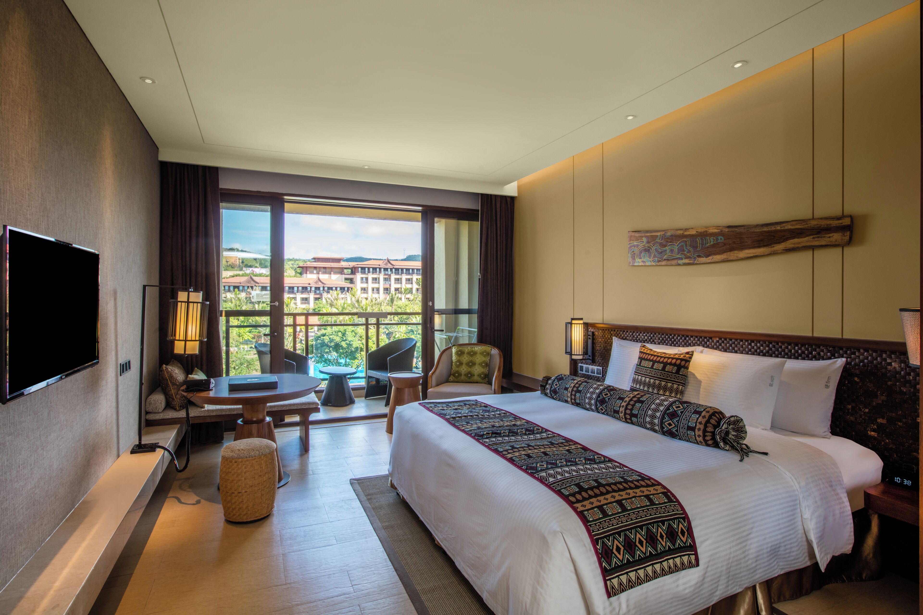 Une chambre d’hôtel avec un grand lit, une télévision, un balcon avec vue et un coin repas.