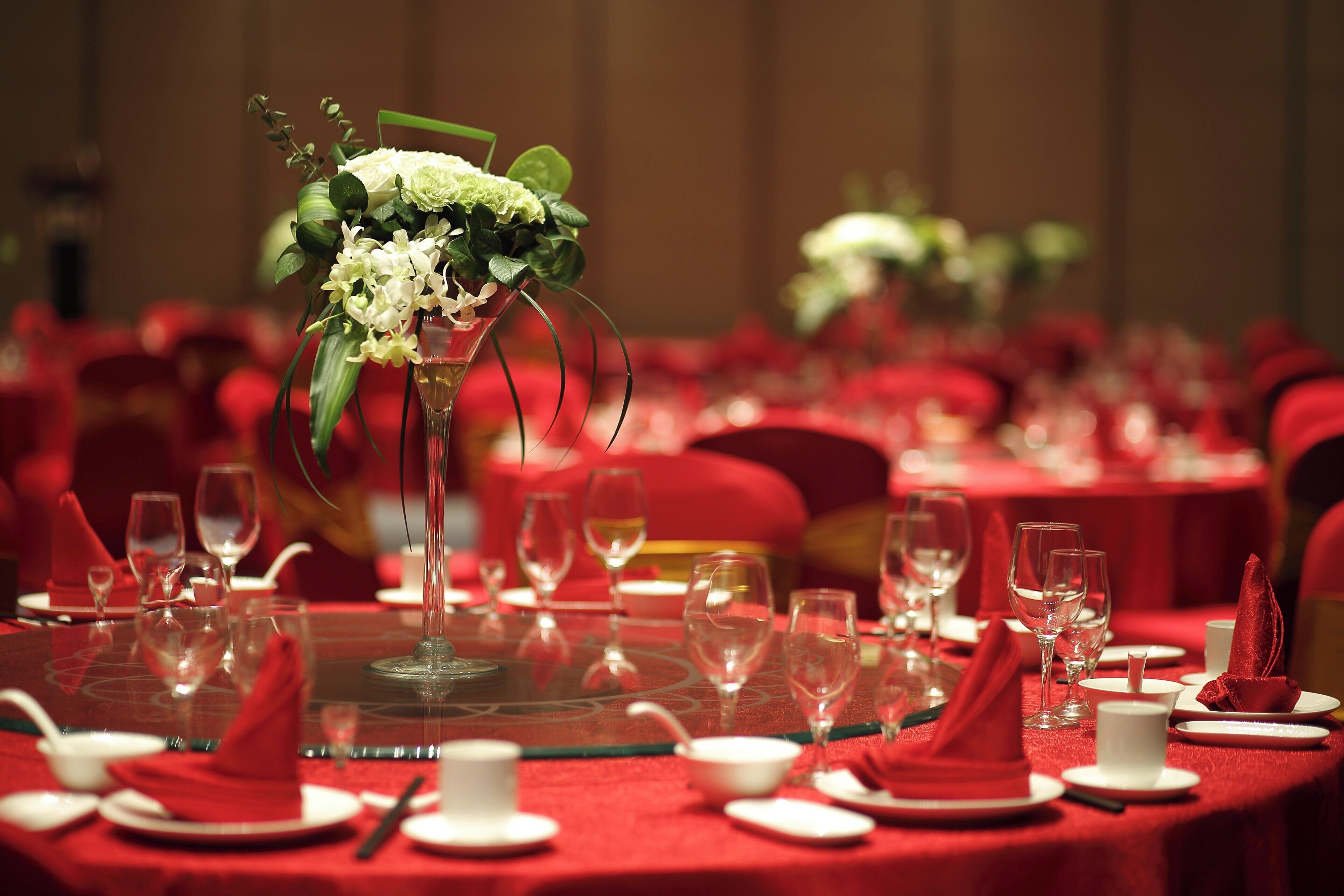 A banquet table set with red tablecloths, white plates, and clear glassware.