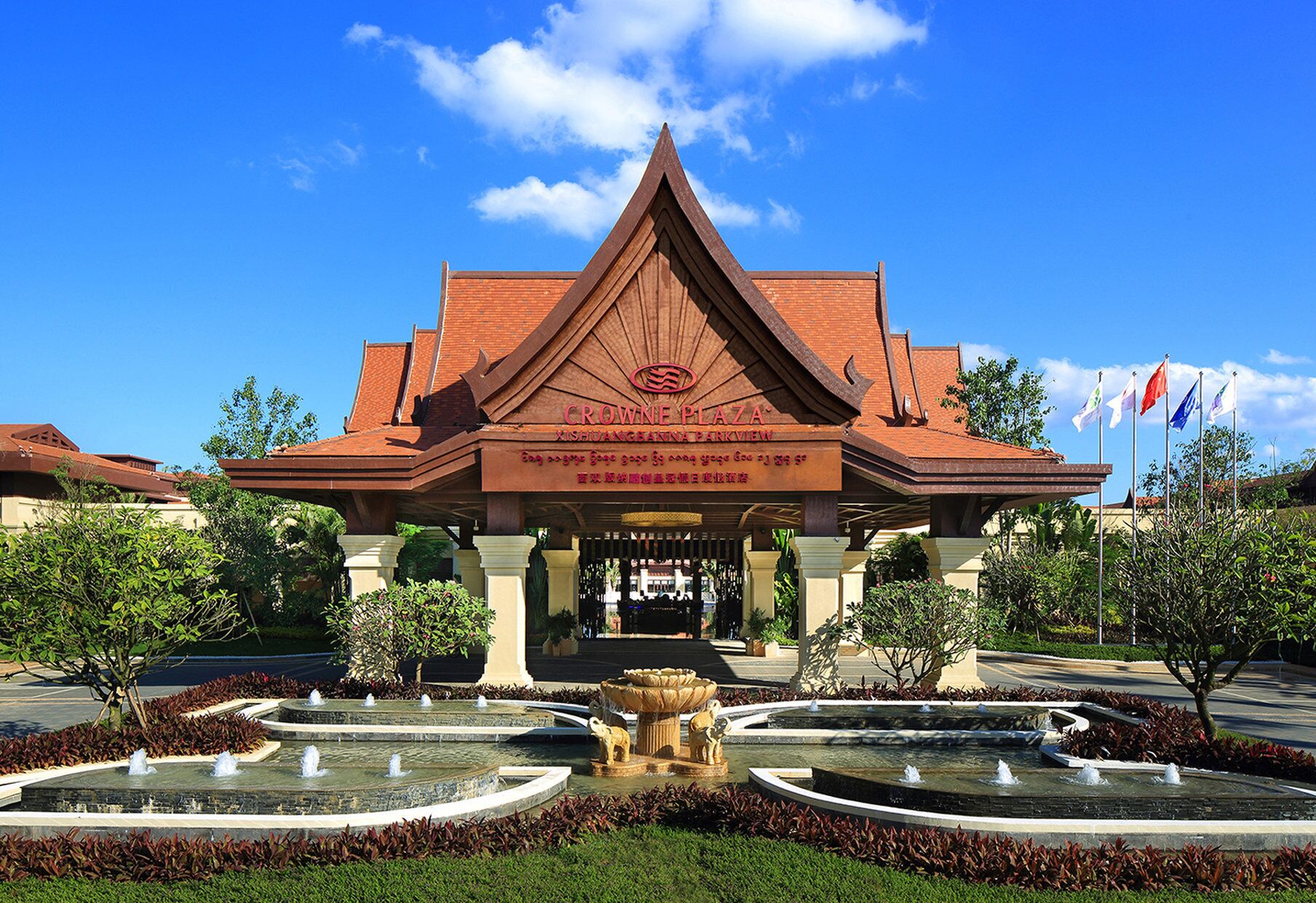 A building with a traditional architectural style, a sign reading 'CROWNE PLAZA,' and a landscaped fountain area.