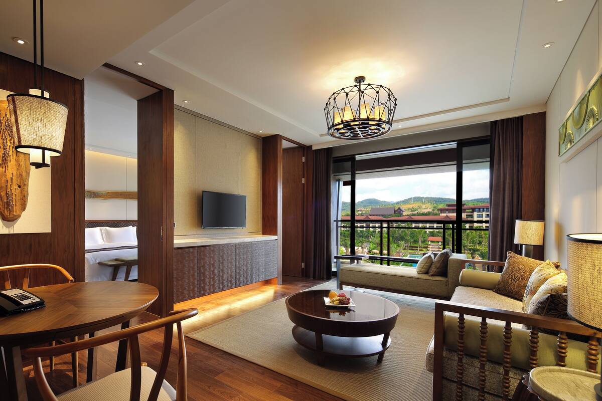 Ein modernes Hotelzimmer mit Essbereich, einer Couch und Blick sowie einem Fernseher.