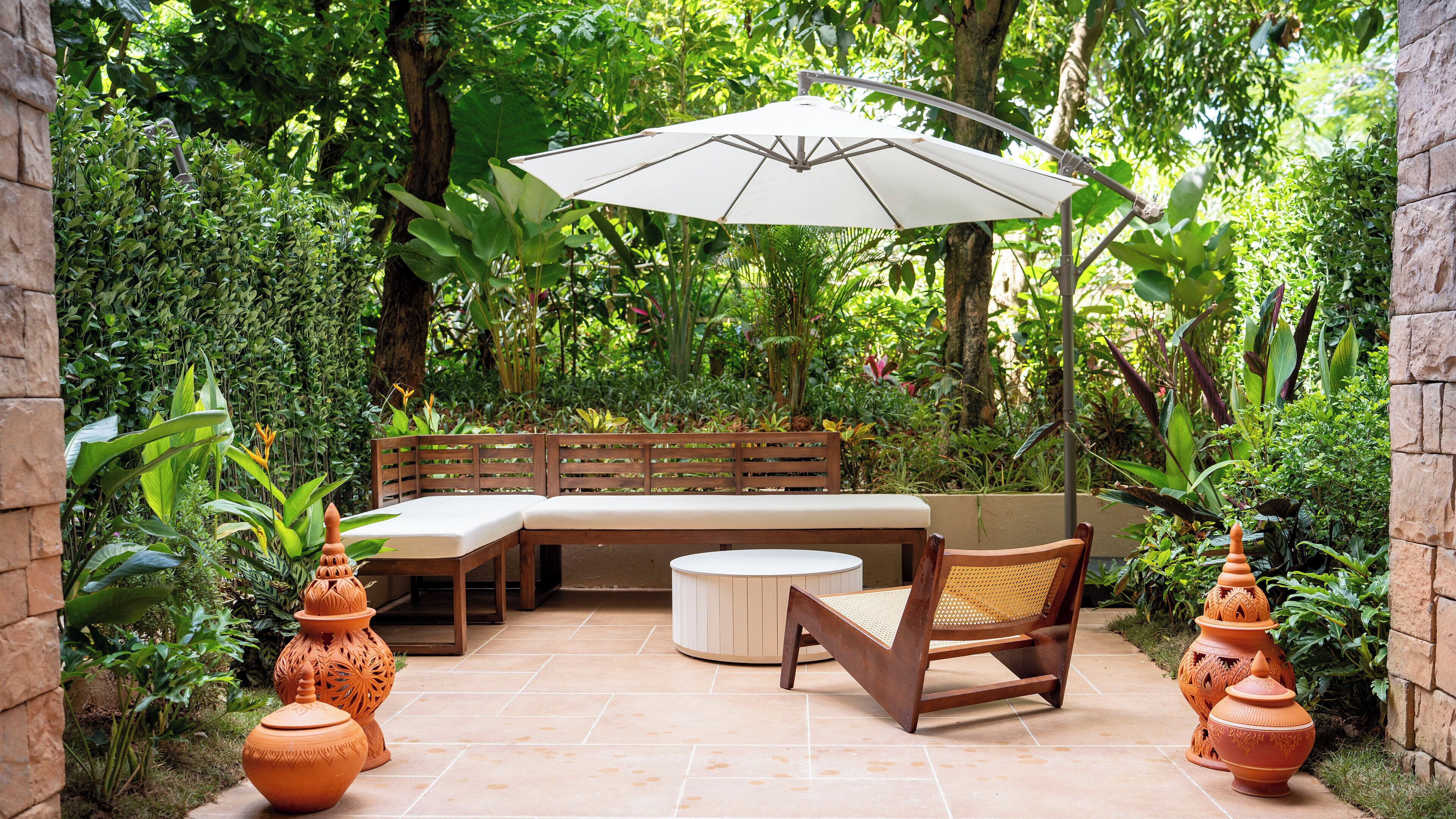 A patio with a wooden bench, a round table, and an umbrella.