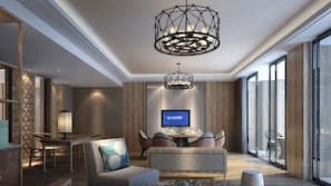 A modern living room with a large TV, a dining area, and a seating area with a patterned sofa and a decorative lamp. - Crowne Plaza Resort Xishuangbanna Parkview by IHG (Xishuangbanna Dai)