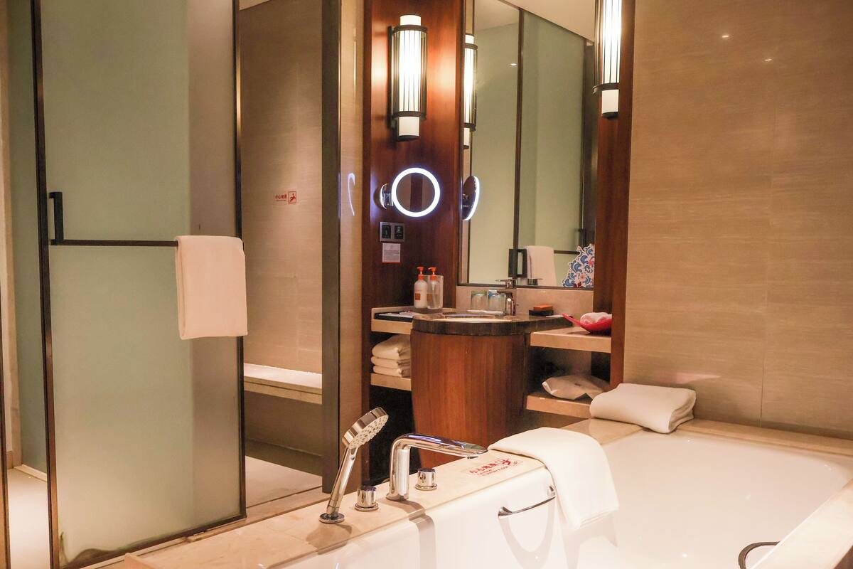 Ein modernes Badezimmer mit einer großen Badewanne, einem Waschtisch mit Spiegel und einer Duschkabine aus Glas.