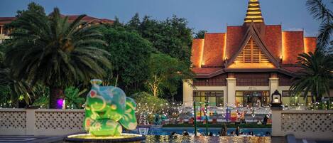 A building with a traditional architectural style, a large fountain, and a pool area.