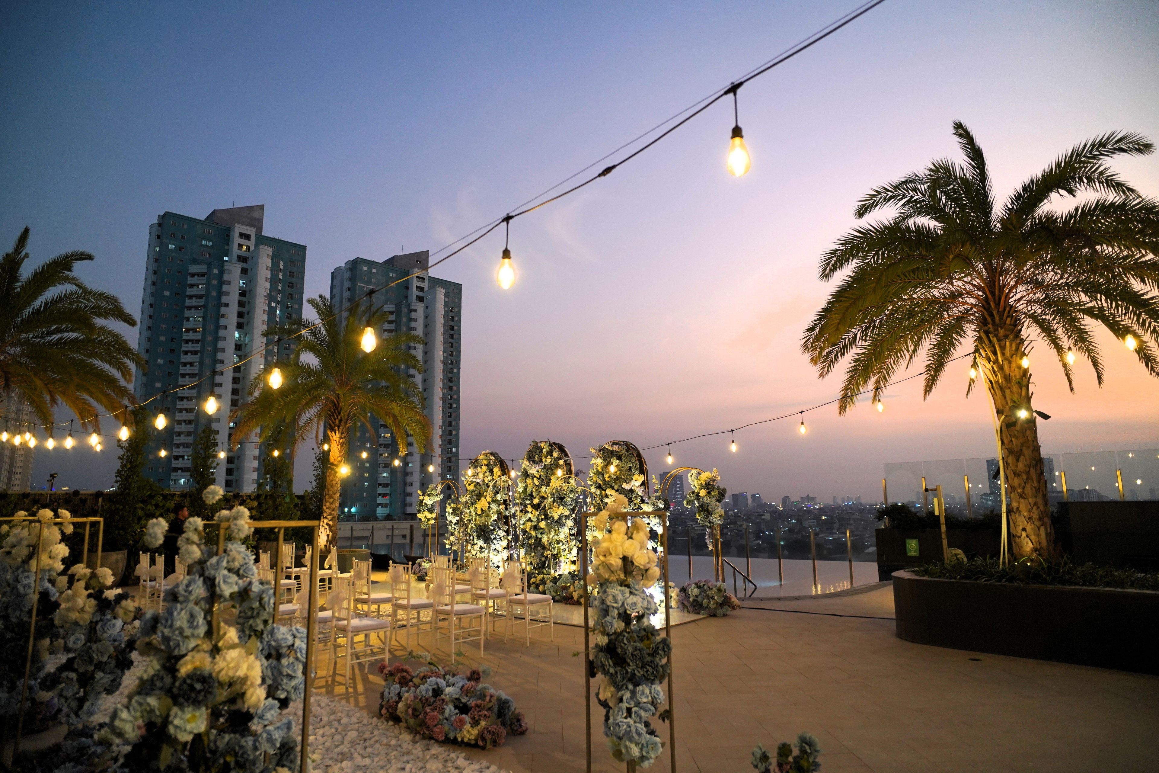 An outdoor event space with string lights, floral arrangements, and seating.
