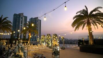 An outdoor event space with string lights, floral arrangements, and seating.