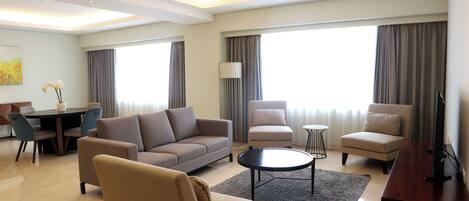 A modern living room with a sofa, armchairs, a coffee table, and a TV stand.