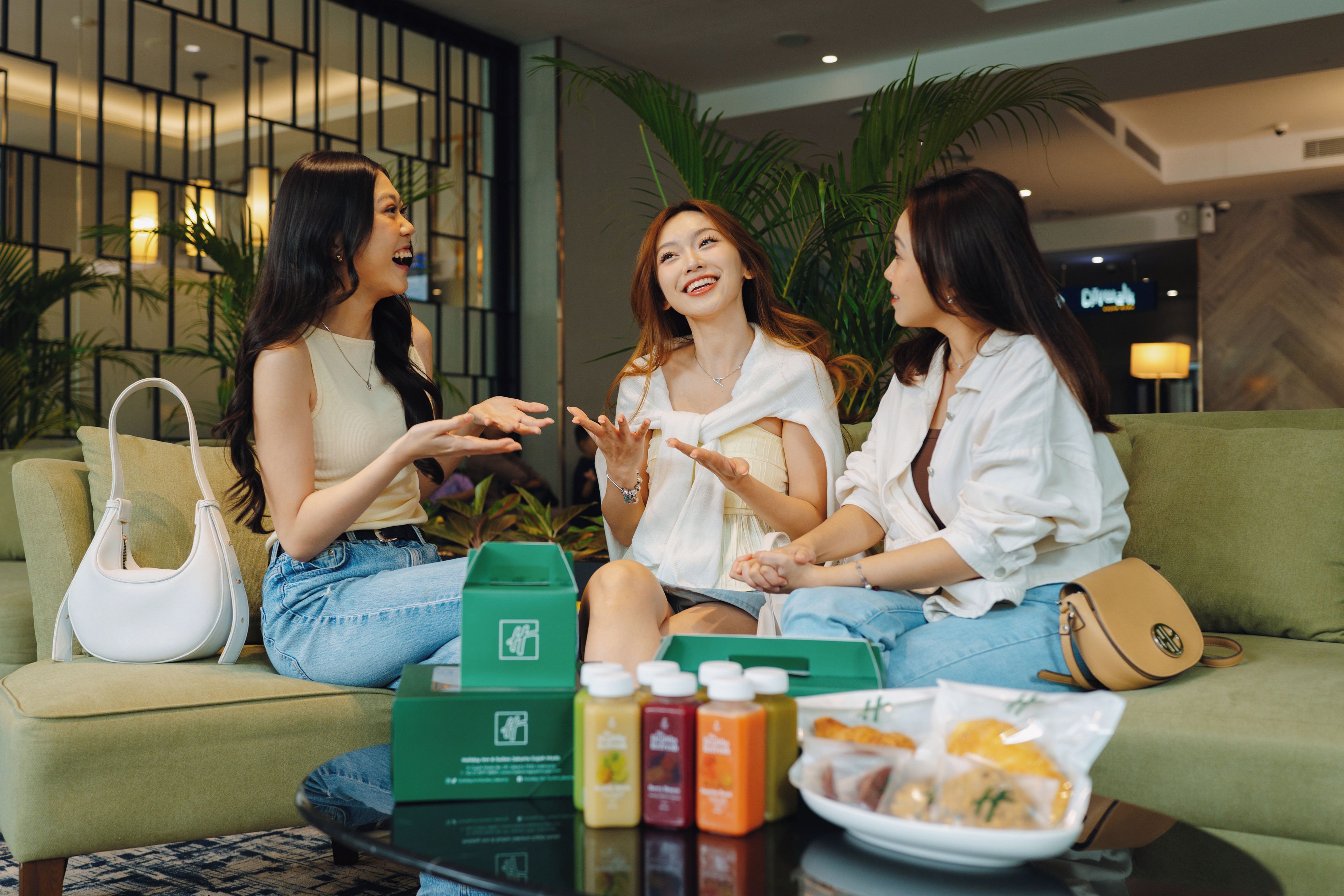 Tres personas sentadas en un sofá en un ambiente interior moderno, con una mesa de centro frente a ellas.