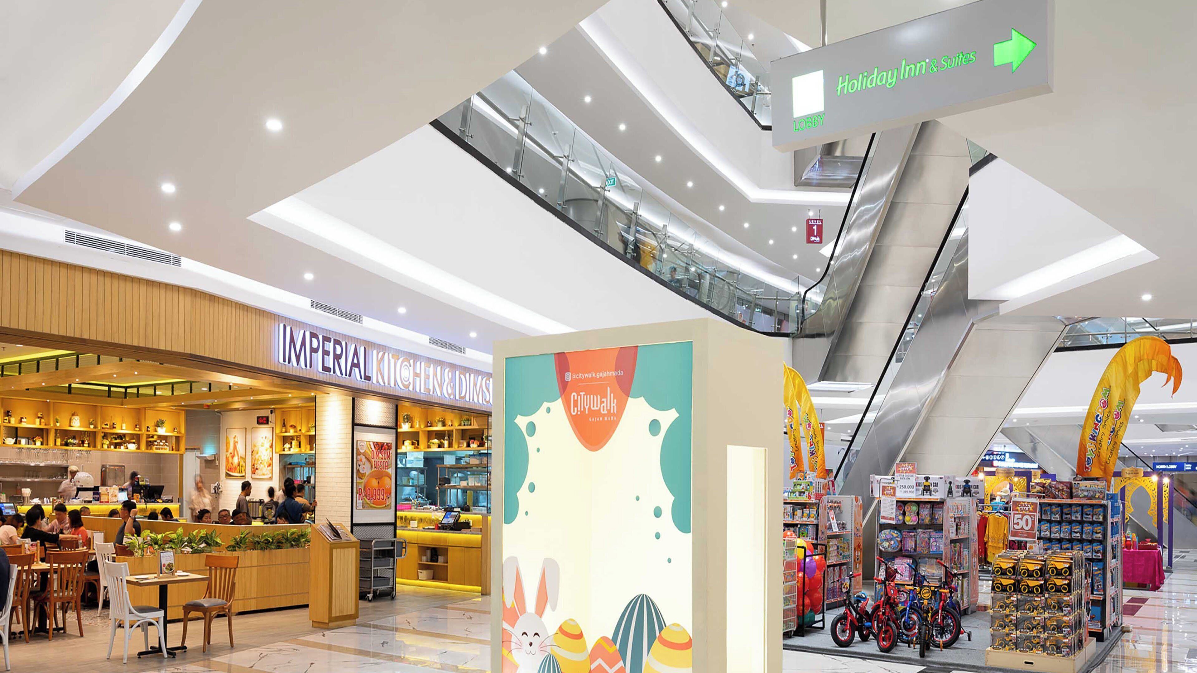 A shopping mall with a restaurant named 'Imperial Kitchen & Deli,' a 'City Walk' promotional sign, and an 'Holiday Inn & Suites' sign.