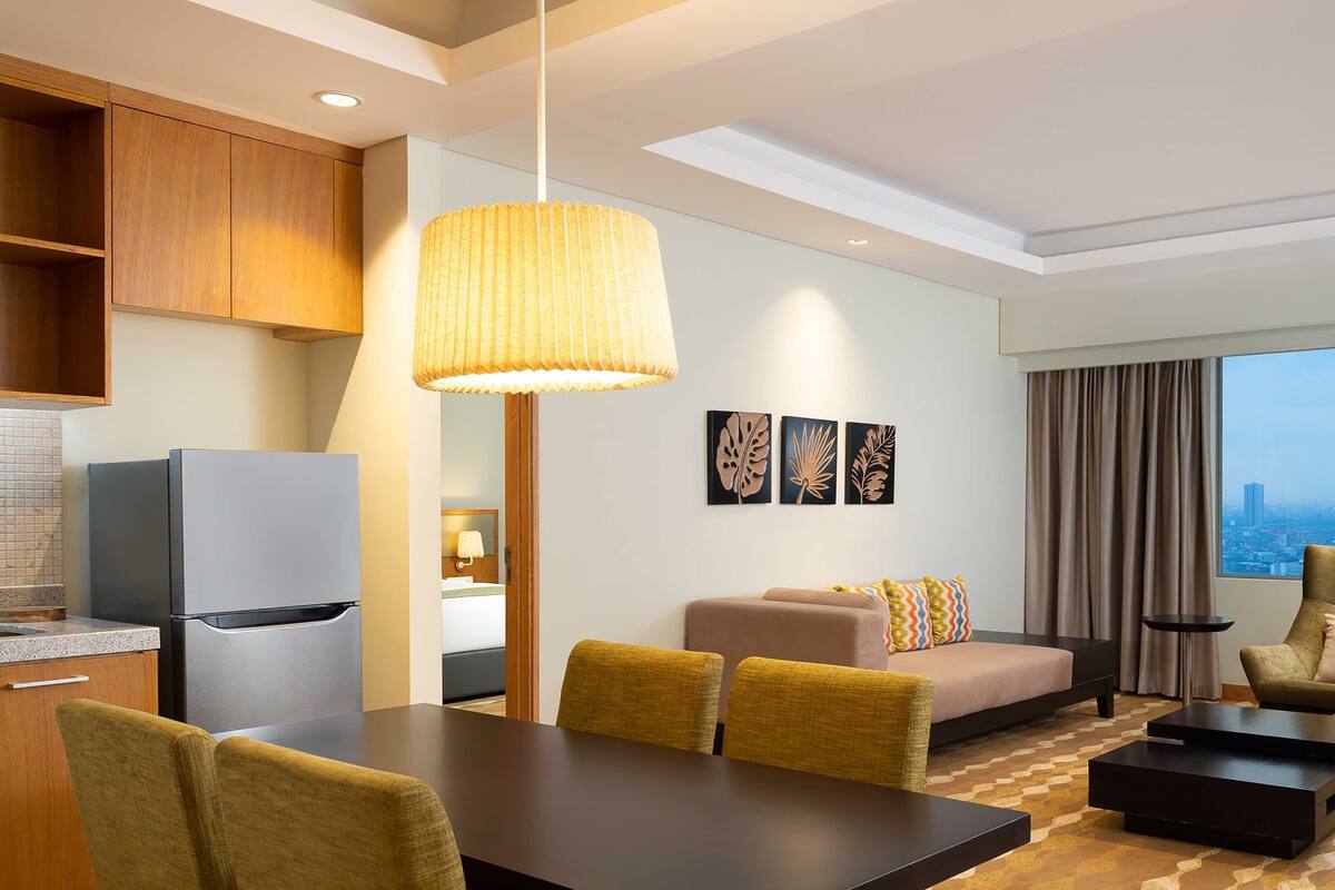 Een moderne hotelkamer met een zithoek, een bank, een bijzettafeltje en uitzicht op de stad.