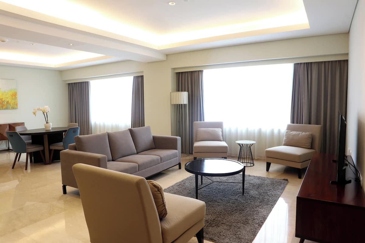 Een moderne woonkamer met een bank, fauteuils, een salontafel en een tv-meubel.