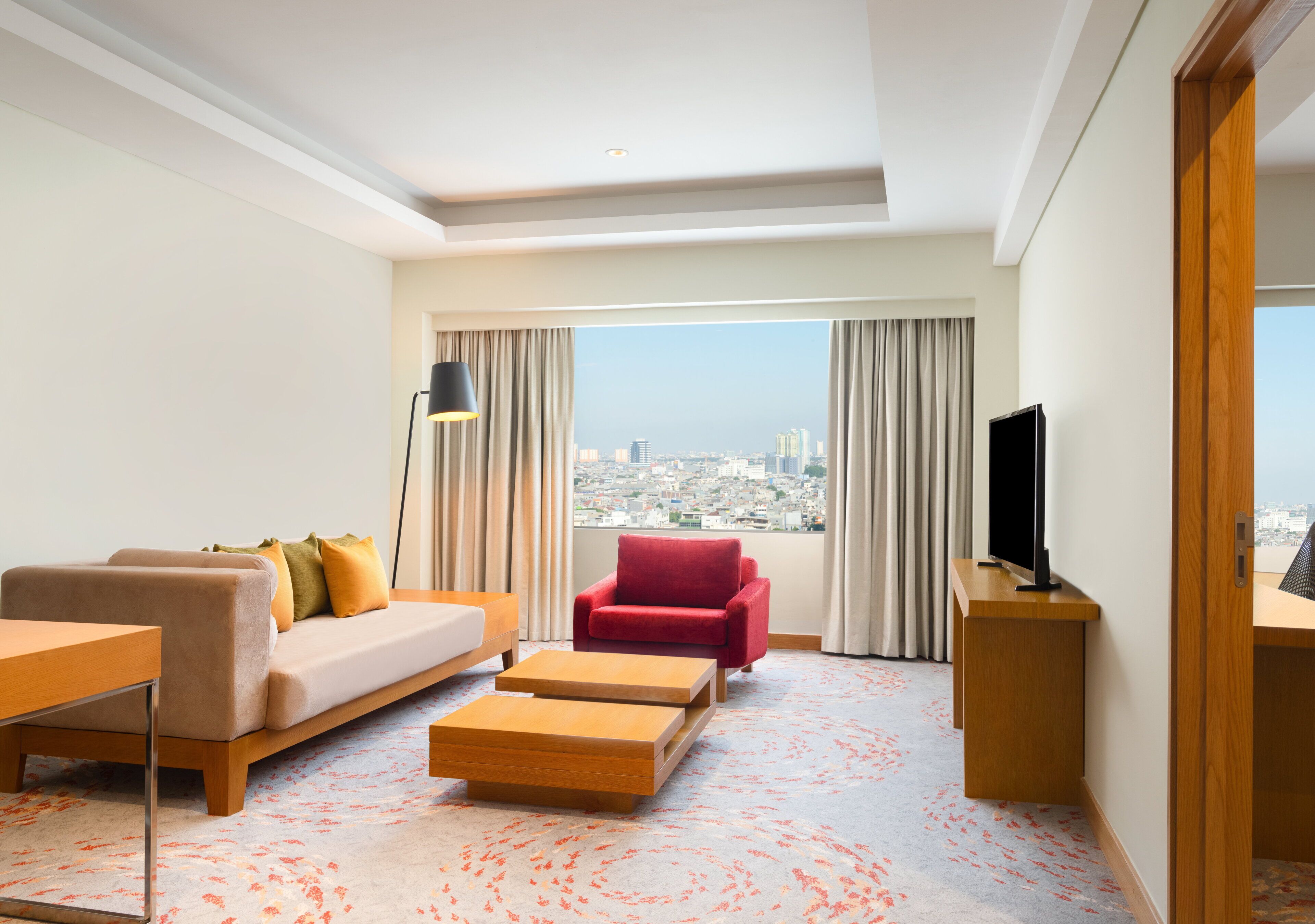 Ein Hotelzimmer mit einer Couch, einem Sessel und einem Fernseher auf einem Holzboden.