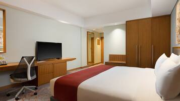 Una habitación de hotel con cama, televisión, escritorio y armario.