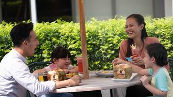 Guests can enjoy meals and drinks in a serene outdoor setting surrounded by lush greenery.