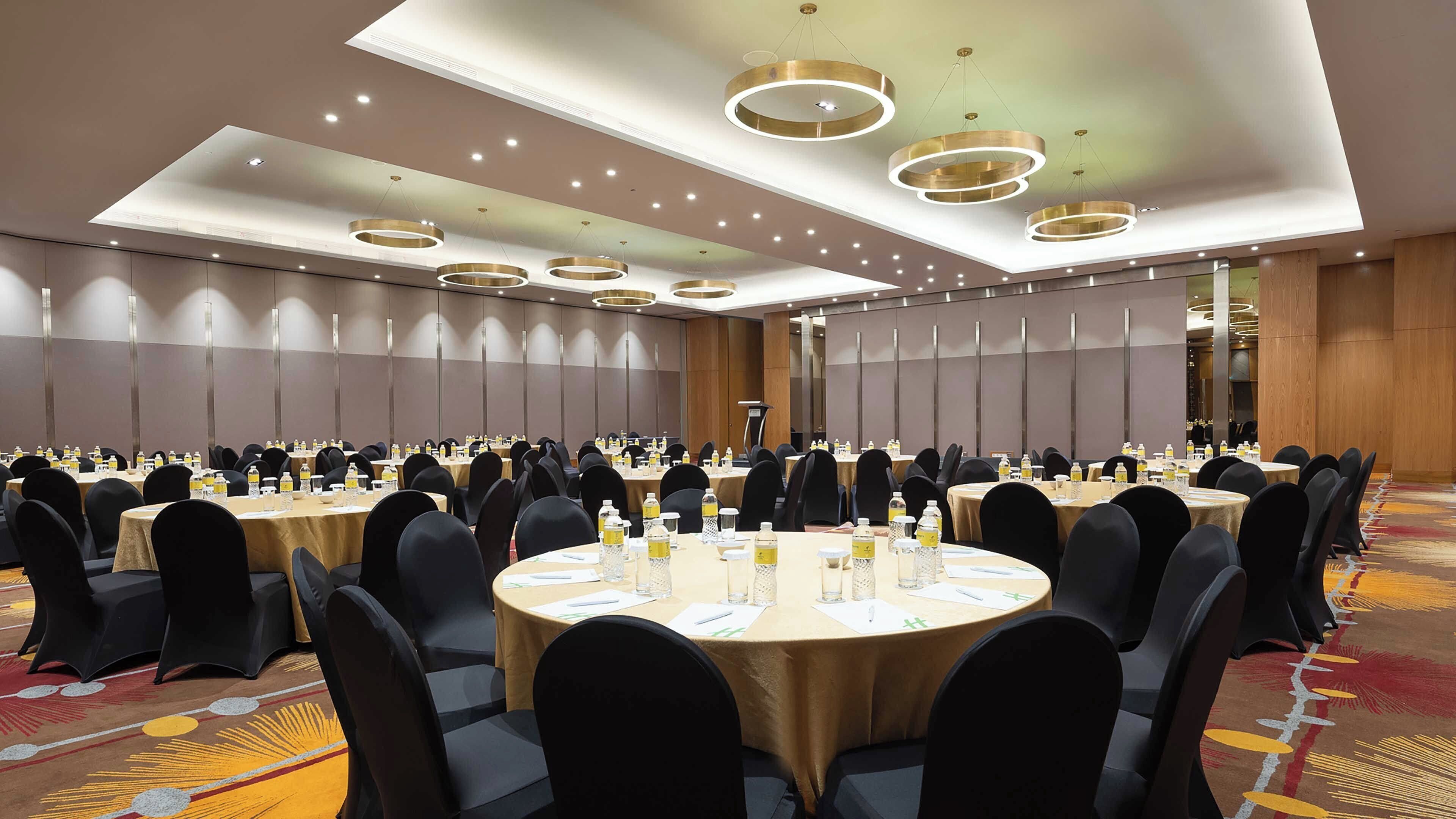 Een congreszaal met meerdere tafels, stoelen en een spreekgestoelte.