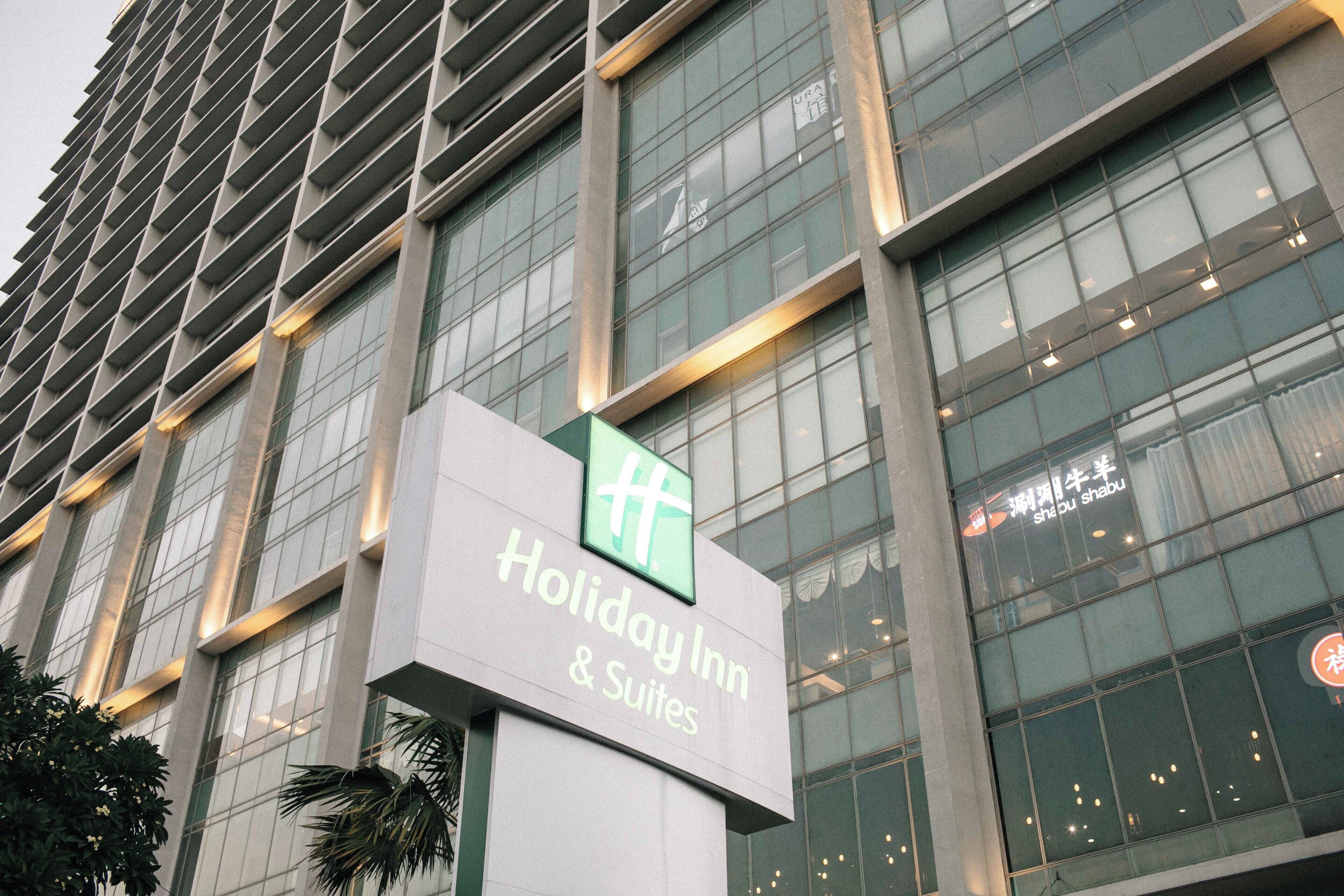 Une enseigne d’hôtel portant le nom « Holiday Inn & Suites », qui permet de l’identifier.