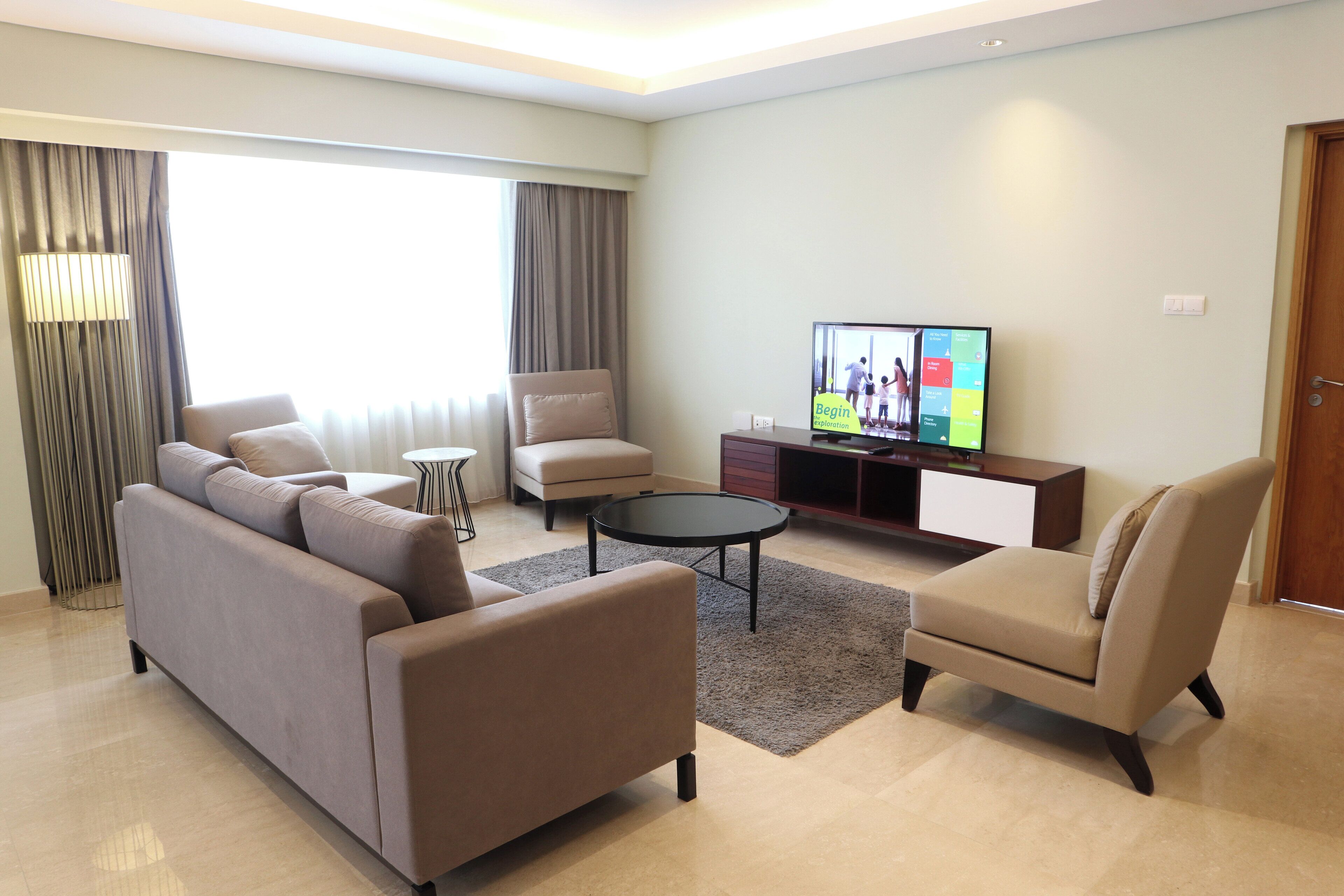 A modern living room with a sofa, armchair, coffee table, and a flat-screen TV.