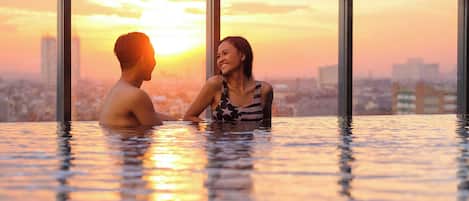 A couple in a heated outdoor pool with a cityscape in the background.