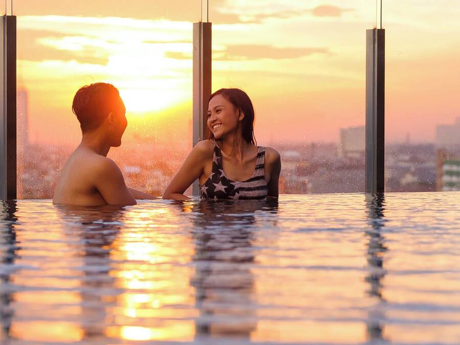 A couple in a heated outdoor pool with a cityscape in the background.