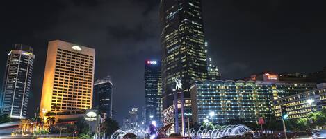 A nighttime cityscape with illuminated skyscrapers and a busy street with light trails.