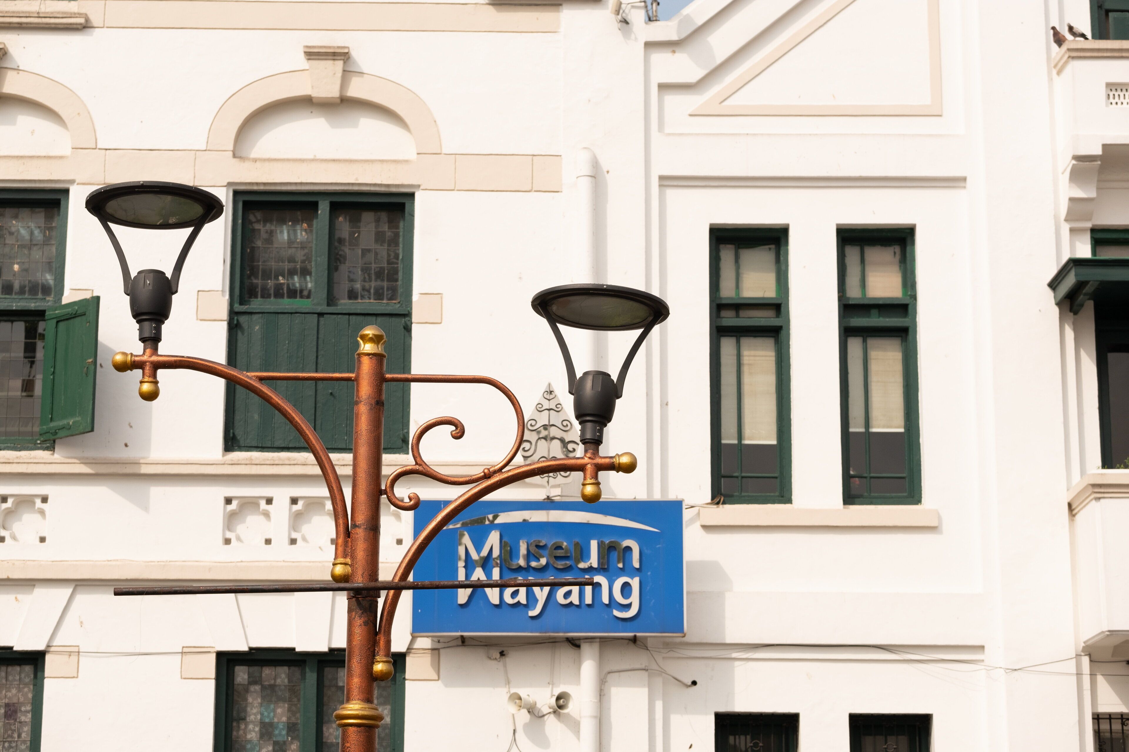 Un lampadaire à trois lampes et un panneau indiquant « Museum Wayang ».