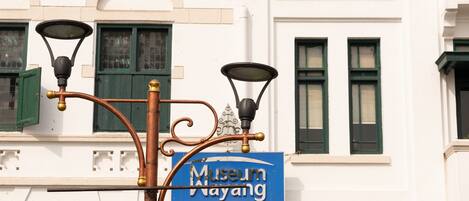 A street lamp with three lights and a sign for 'Museum Wayang'.