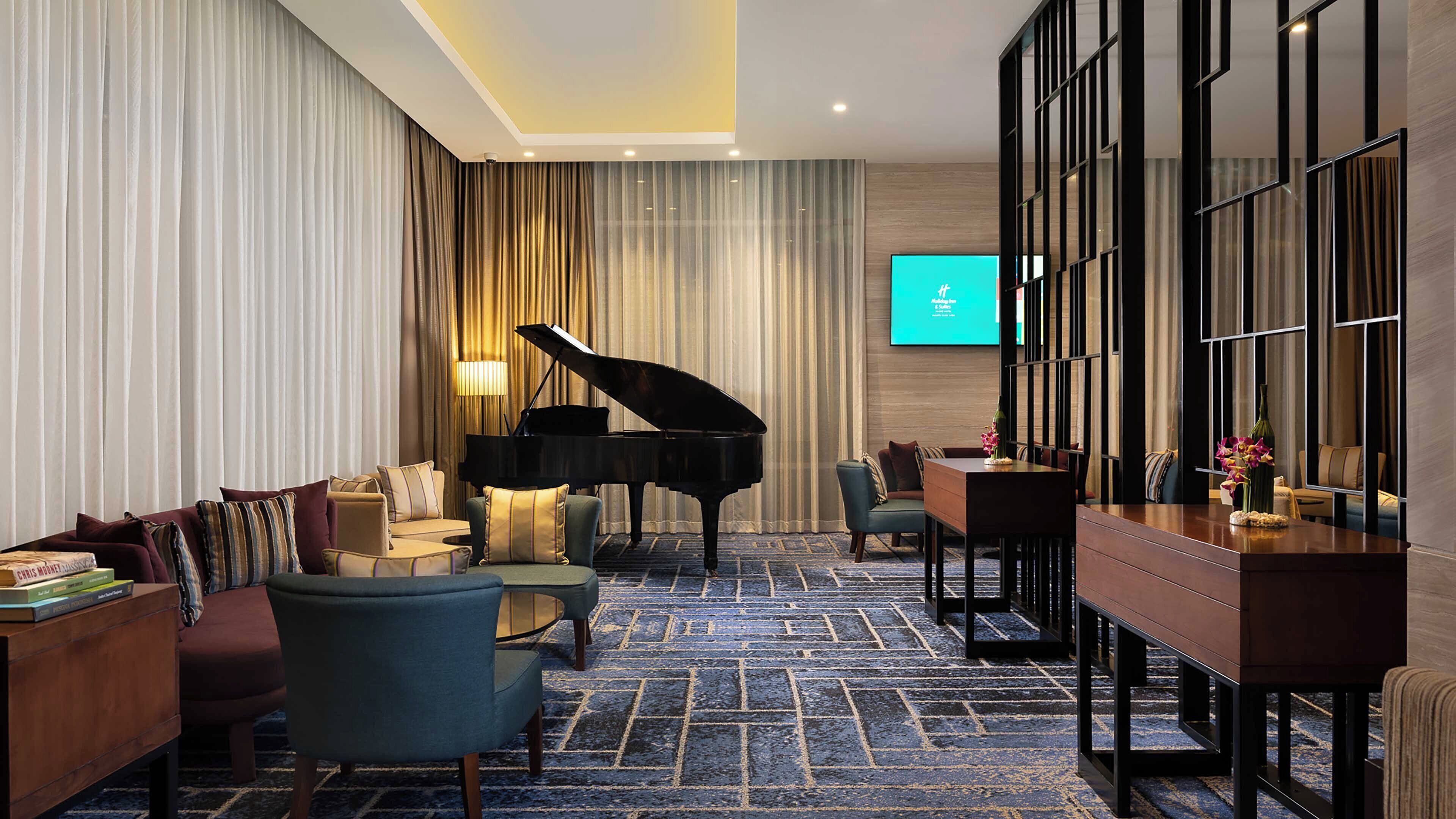 Eine Hotellobby mit einem Flügel, bequemen Sitzgelegenheiten, einem Fernsehbildschirm und einer modernen Einrichtung.