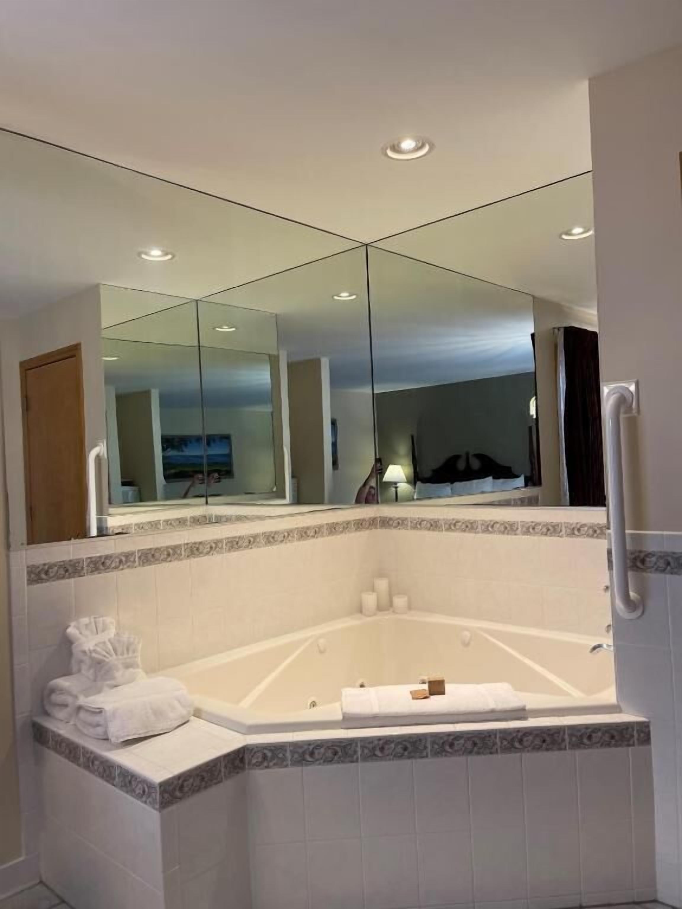 A bathroom with a large mirror, a bathtub, and a towel rack.