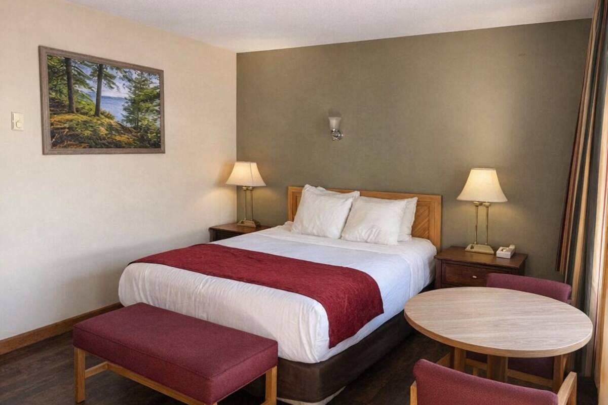 A hotel room with a bed, two bedside tables, a round table, and two chairs.