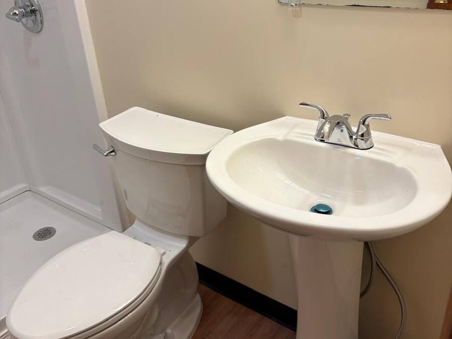 Un baño con inodoro y lavamanos sobrepedal.