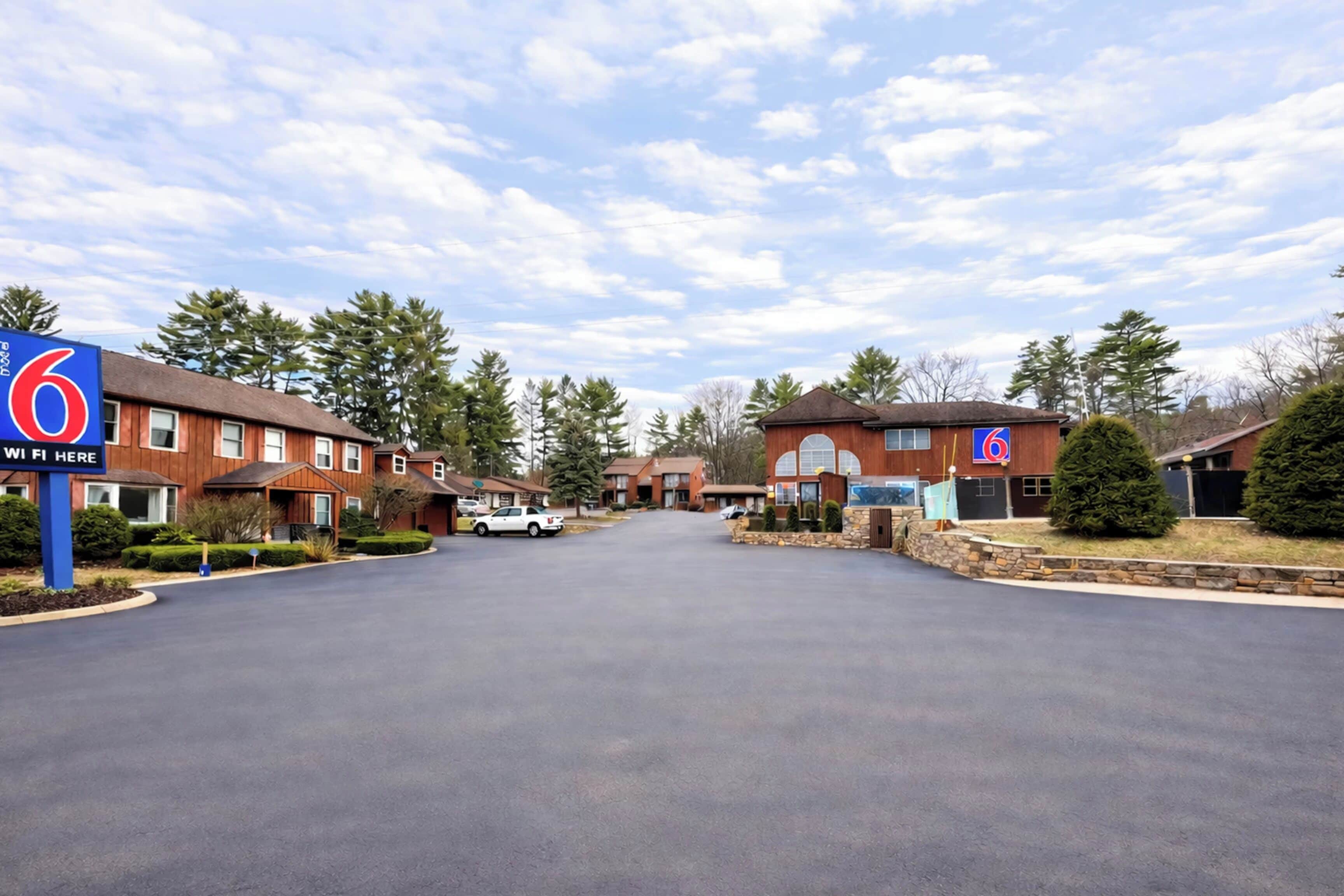 A 6 Motel with a clear driveway, multiple buildings, and a sign indicating WiFi availability.