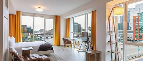 Una habitación de hotel moderna con una cama grande, un escritorio y vistas a la ciudad.
