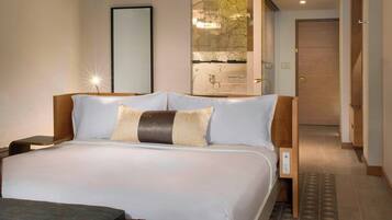 Una habitación de hotel con una cama grande, un aparador de madera, un reposapiés de cuero y un mapa en la pared.