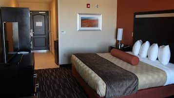 Una habitación de hotel con cama, escritorio, silla, televisor y puerta.