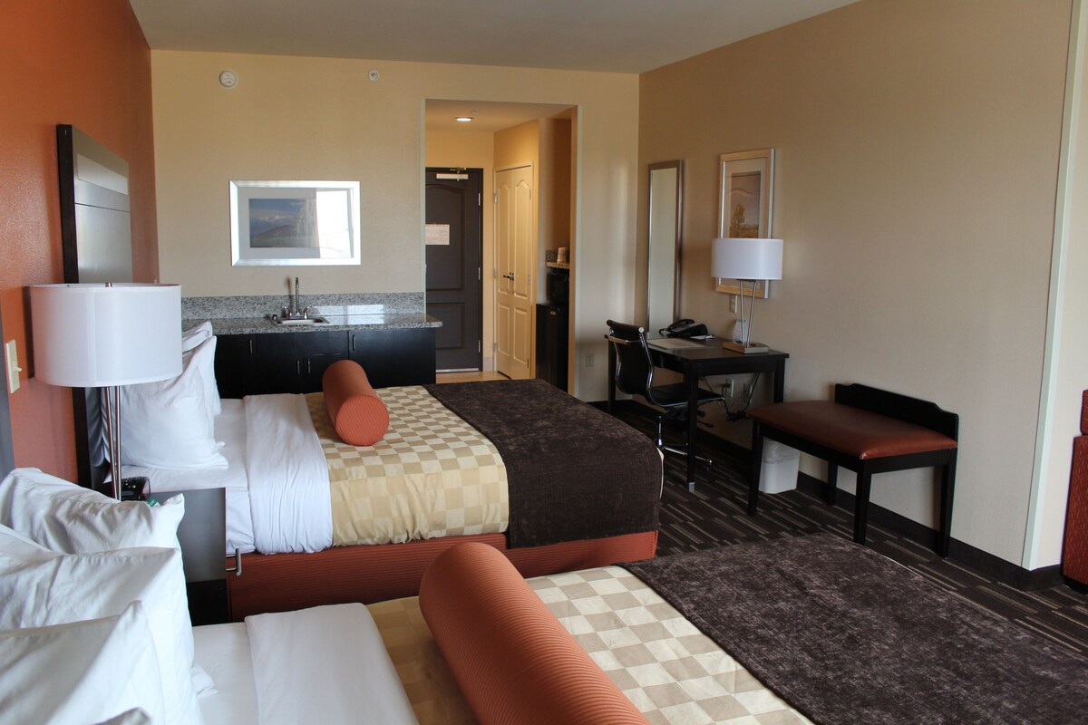 Habitación de hotel con cama, escritorio, silla, baño y vista al exterior.