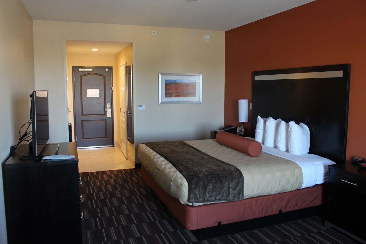 Habitación de hotel con cama, escritorio, televisión y puerta que da a otra habitación.