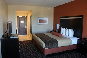 Habitación de hotel con cama, escritorio, televisión y puerta que da a otra habitación.