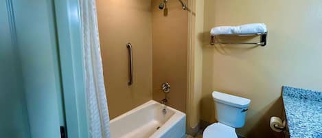 A bathroom with a bathtub, toilet, and a towel rack.