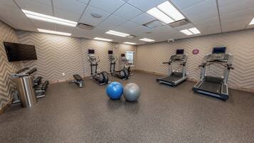 A gym with treadmills, elliptical machines, and exercise balls.