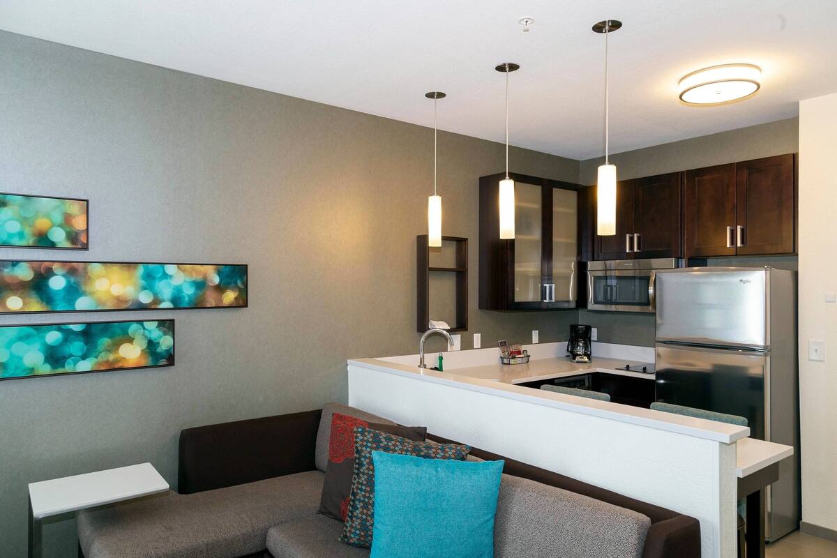 A modern kitchen with stainless steel appliances, a white countertop, and pendant lighting.