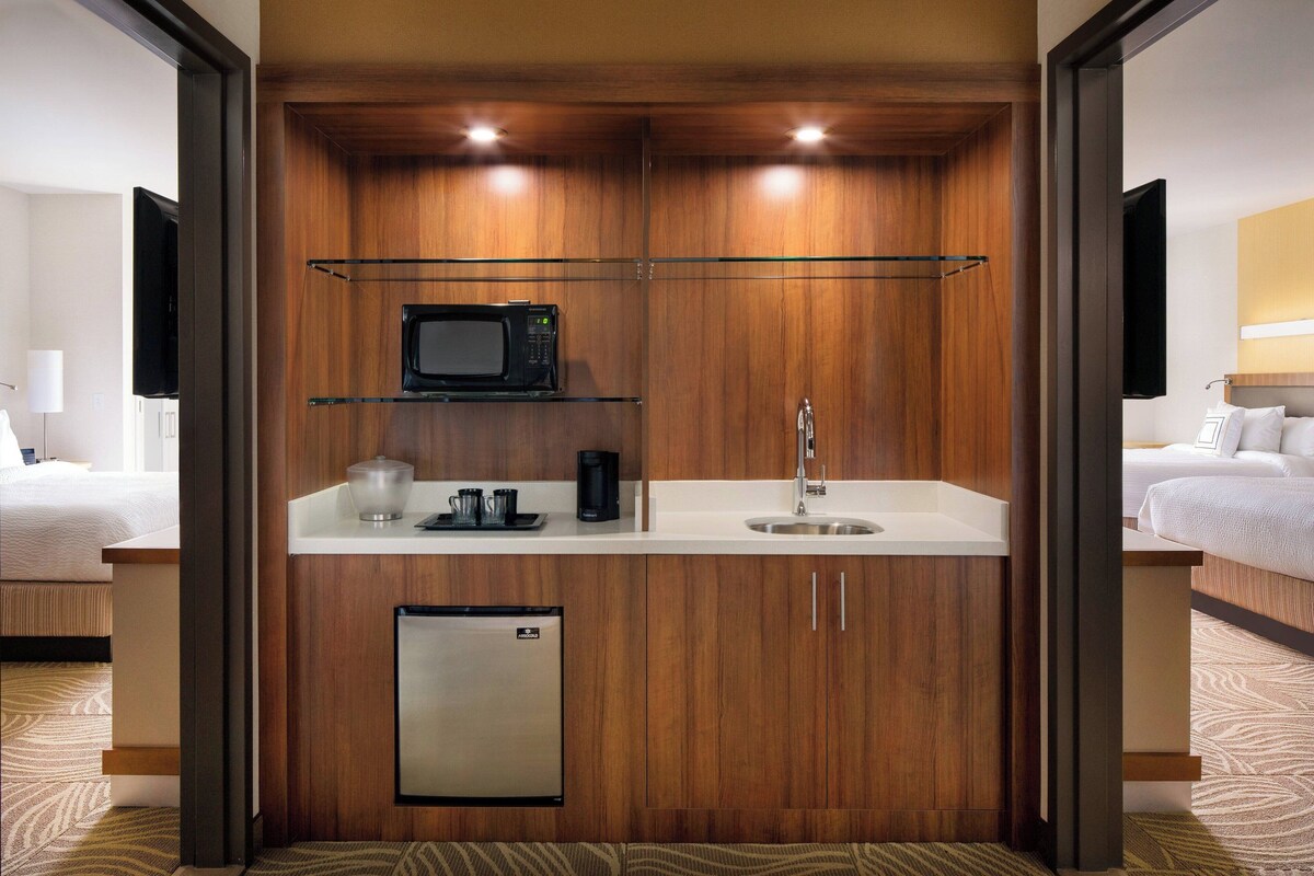 A compact hotel room with a kitchenette including a microwave, coffee maker, and mini-fridge.