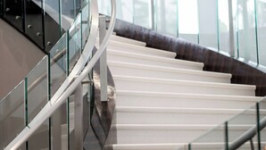 Una escalera moderna con barandillas de vidrio y un diseño curvo.