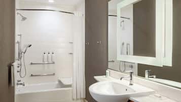 Un baño moderno con bañera, ducha y un espejo grande sobre el lavamanos.