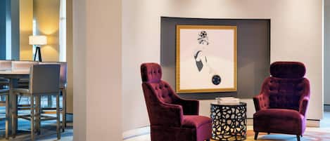 Un área de estar moderna con dos sillones cómodos, una mesa redonda y una obra de arte enmarcada en la pared.
